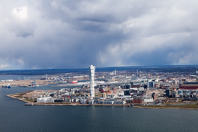 Utsikt över Malmö från luften ovanför vattnet. I mitten syns Turning Torso.