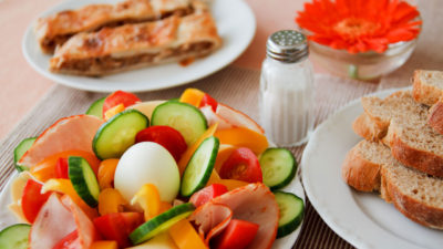 En stor frukost med ägg, grönsakger och bröd fint upplagt på ett ljust bord.