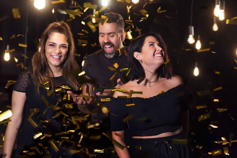 Farah. Kalle och Molly skrattar och ler. De har svarta kläder på sig och det regnar ner guldkonfetti över dem.