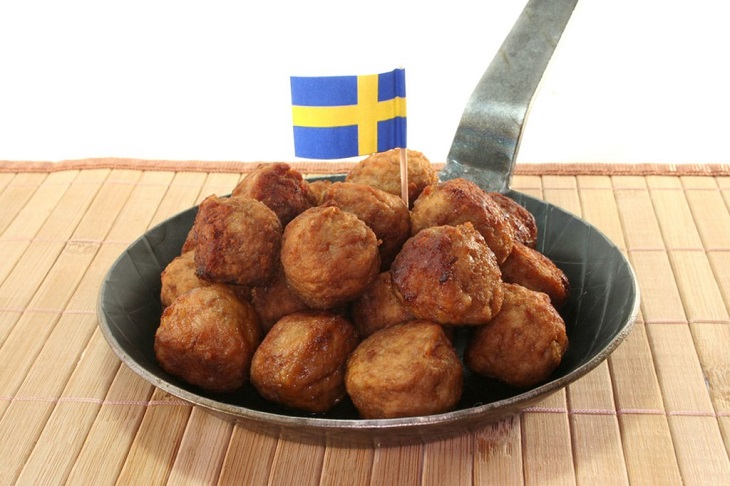 En liten stekpanna med en hög av köttbullar i. Istucket bland köttbullarna är en liten svensk flagga.