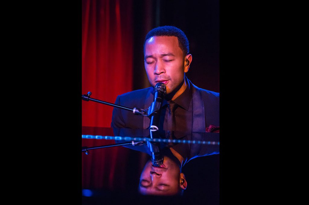 John Legend sitter och sjunger bakom ett piano
