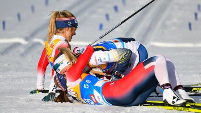 Frida Karlsson och två andra skidåkare ligger ner i snön och kramas efter att ha passerat mållinjen i skid-VM.