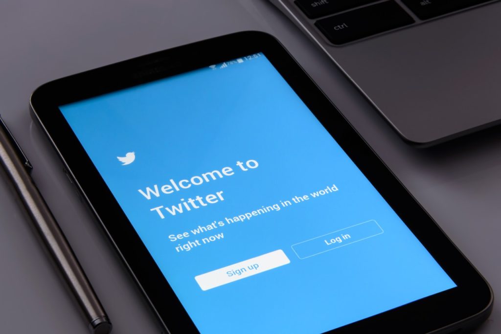 Bild på en surfplatta som ligger på ett bord. På surfplattan syns förstasidan till Twitter.